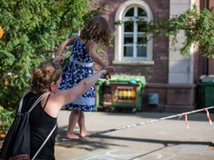 eine junge Frau spielt mit ihrer Tochter auf dem Campus