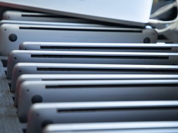 Mehrere Laptops liegen hochkant in einem Ständer und sind an Ladekabel angeschlossen.