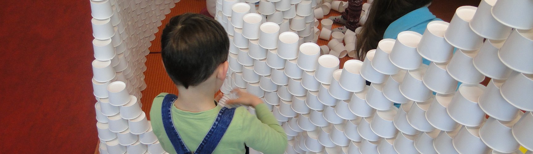 Ein Kind baut hohe Mauern aus Eisbechern.