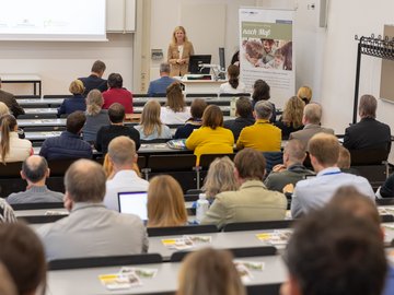 Eine Frau spricht in einem Hörsaal vor Publikum.