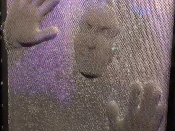 Gesicht- und Handabdruck sind durch eine formbare Masse zu sehen.