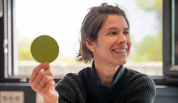 Eine Person hält einen grünen Punkt aus Papier in die Höhe.