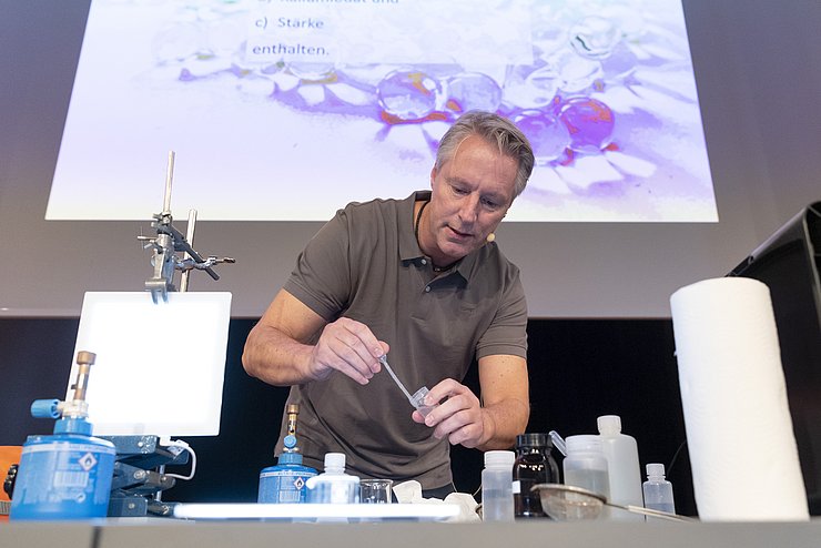 Prof. Ducci beim Experimentieren mit Pipette, Becherglas, Chemikalien und Bunsenbrenner.