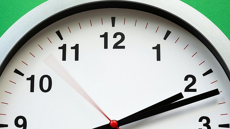 Weiße Uhr Eine weiße Uhr mit schwarzen Ziffern vor einem grünen Hintergrund