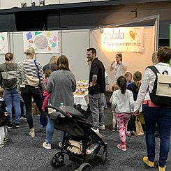 Kinder und Erwachsene von hinten, wie sie mit großem Interesse bei der MitmachStation "Mit Eiskugeln Farbkombinationen herausfinden" beim Stand der PHKA auf den Sience DAys für Kinder 2023 anstehen.