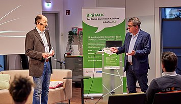 Im vom Hammer Photographie zur Verfügung gestellten Bild seiht man den Moderator Uwe Gradwohl (links) und Prof. Dr. Christian Gleser vor einem RollUp im Gespräch.