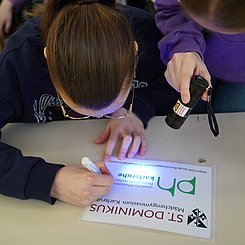Eine Schülerin, die mit Hilfe eines UV-Stifts ihren Namen auf den Sondenflügel schreibt.