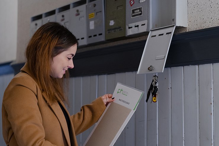 Lehramtsabsolventin Laura Vollweiler holt ihr PHKA-Abschlusszeugnis aus dem Briefkasten. Foto: Roxane Fijean/PHKA
