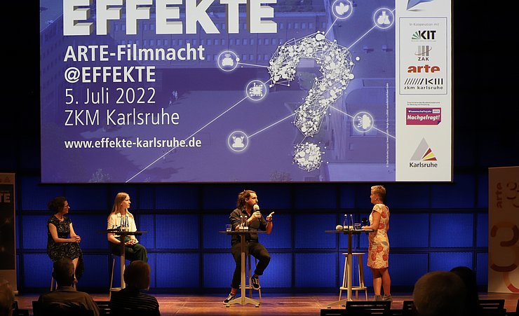 Teilnehmenden der Podiumsdiskussion mit Moderatorin auf der Bühne vor einer Leinwand mit dem EFFKTE-Logo