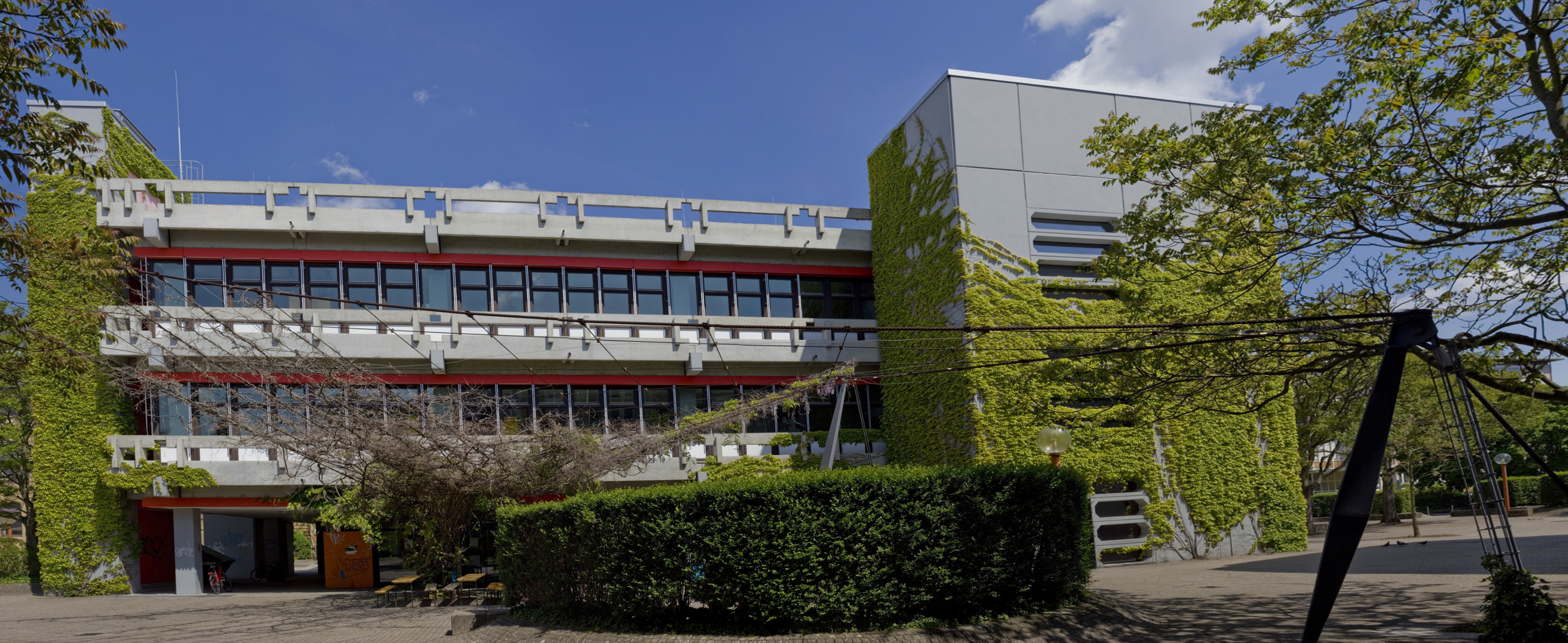 Gebäude 2 von Seitenausgang Gebäude 1 fotografiert. Hecke und Blätterdach vor dem Gebäude. ©PH Karlsruhe